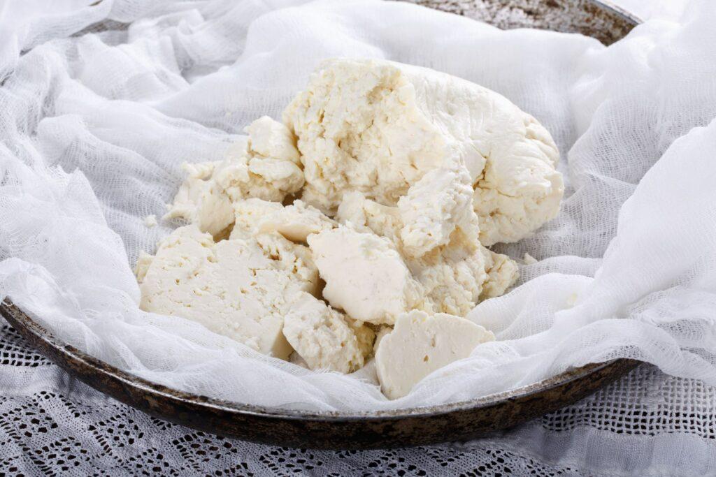 Zerkrümelter weißer Ziegenkäse von lokalen Produzenten aus dem Norden Teneriffas liegt auf einem strukturierten Tuch in einer rustikalen Schale. Die weiche Textur und die natürlichen Farbtöne vermitteln Frische und Einfachheit.
