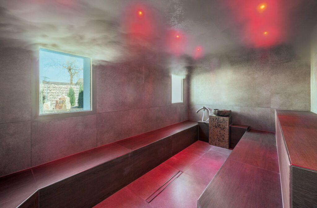 Steam room with two rectangular windows, red benches, and steam at the Lifestyle Resort Zum Kurfürsten in Bernkastel-Kues