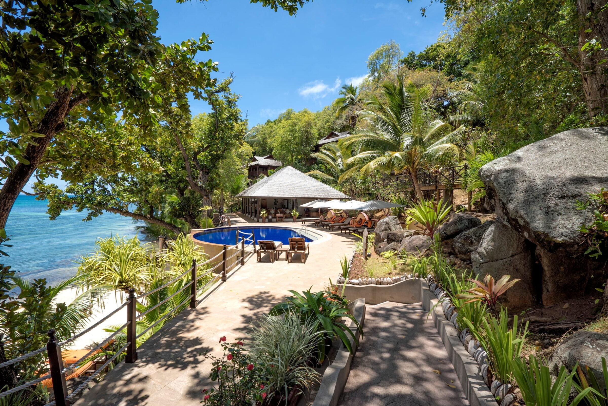 Weg mit Pflanzen und Sitzgelegenheiten führt zu kleinem Pool und überdachtem Bereich im nachhaltigen Cerf Island Resort auf den Seychellen
