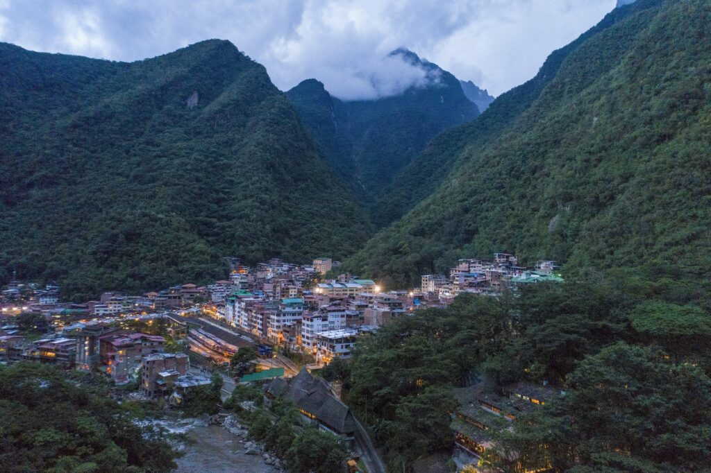 Das Machu Picchu Pueblo Hotel liegt eingebettet in einem üppig grünen Andental in der Abenddämmerung. Sanfte, leuchtende Straßenlaternen beleuchten die Stadt und vermitteln eine ruhige, friedliche Atmosphäre.