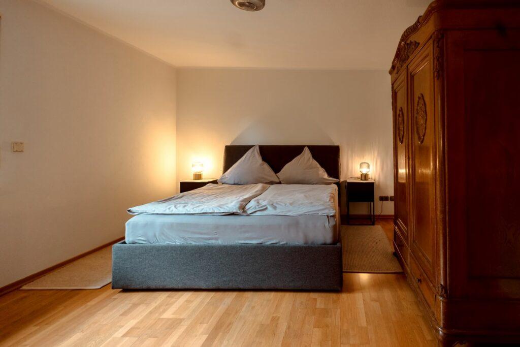 Signature Suite im Eco-Hotel Okelmann's in Warpe, Deutschland. Zu sehen ist ein Bett und ein antiker Kleiderschank, ein nachhaltig aufgearbeites Familienerbstück.