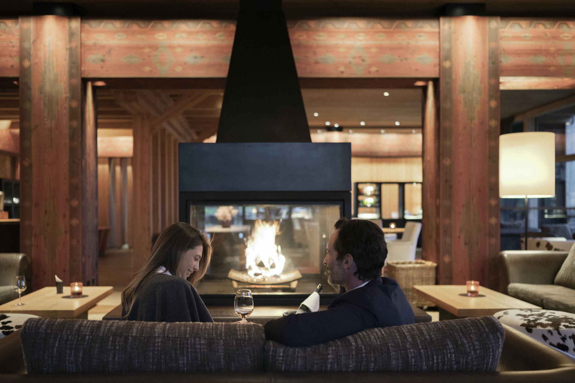 Pärchen vor dem Kamin in der Lounge des nachhaltigen Luxushotels ADLER Lodge RITTEN in Südtirol