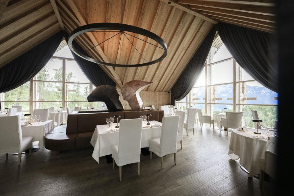 Blick in das nachhaltige Panoramarestaurant der ADLER Lodge RITTEN mit Tischen und Kunstinstallation
