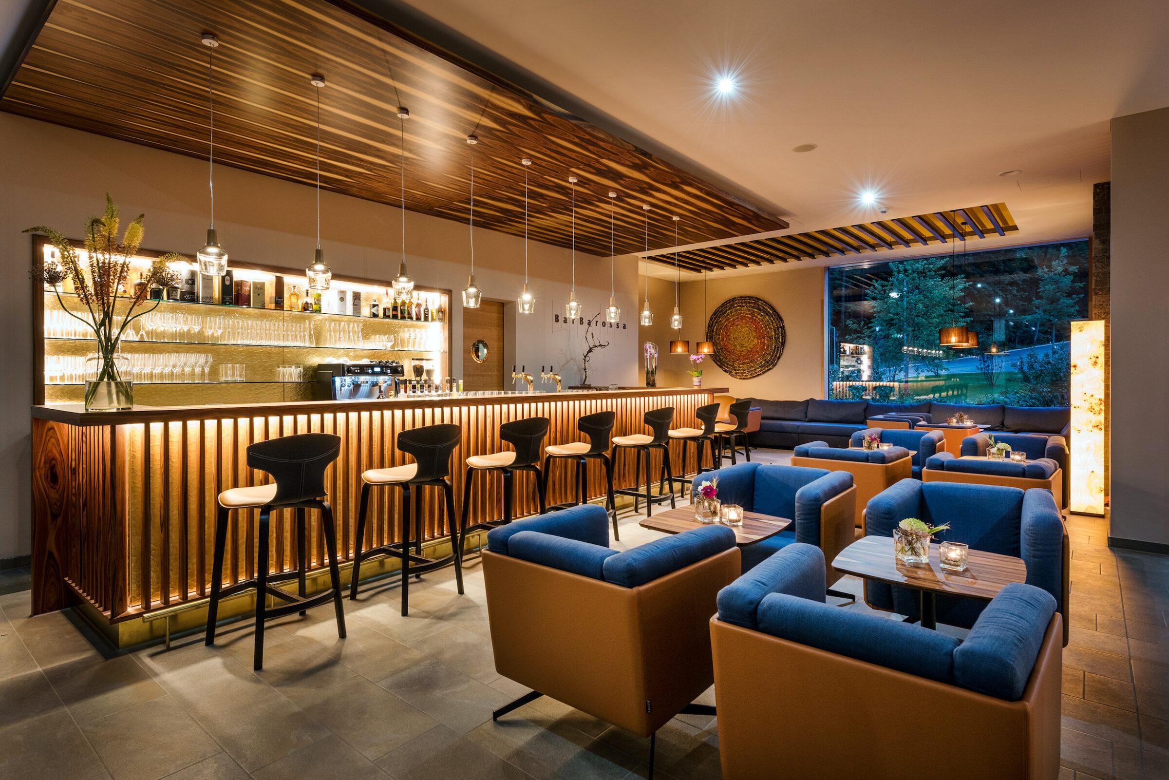 Nachhaltiges Hotel: Klosterhof Alpine Hideaway & Spa - BarBarossa mit blauen polstermöbeln und einer stylischen, holzverkleideten Bar