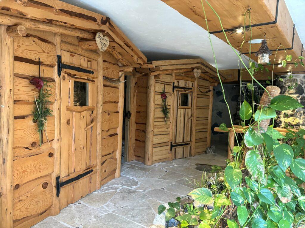 Rustikale Holzsaunakabinen mit Steinboden im Nature Spa des Naturresorts Gerbehof, geschmückt mit herzförmigen Dekorationen und Grünpflanzen. Die gemütliche, natürliche Atmosphäre lädt zum Entspannen ein.