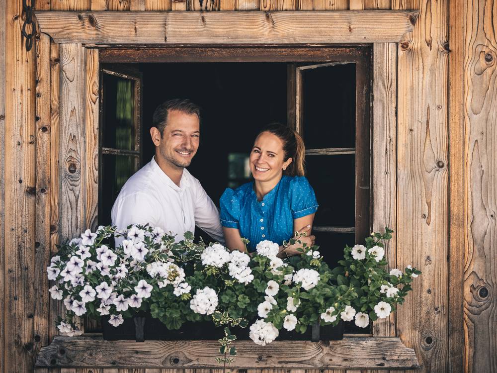 Agnes and Alos Seyrling, chefs and part of the owner family of the Hotel Klosterbräu, looking out of a traditional wooden window