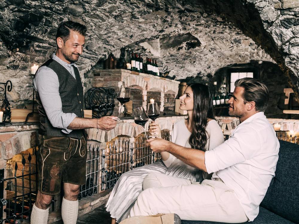 Host Alois Seyrling in the wine cellar serving wine to a couple