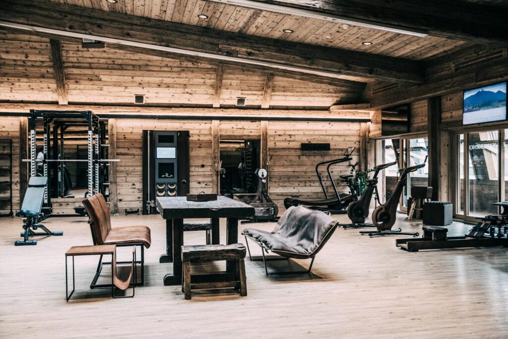 Spacious fitness room with wooden interior, modern training equipment, and rustic furniture at the sustainable wellness hotel Klosterbräu in Seefeld, Tyrol. The atmosphere is cozy and inviting, combining fitness with comfort.