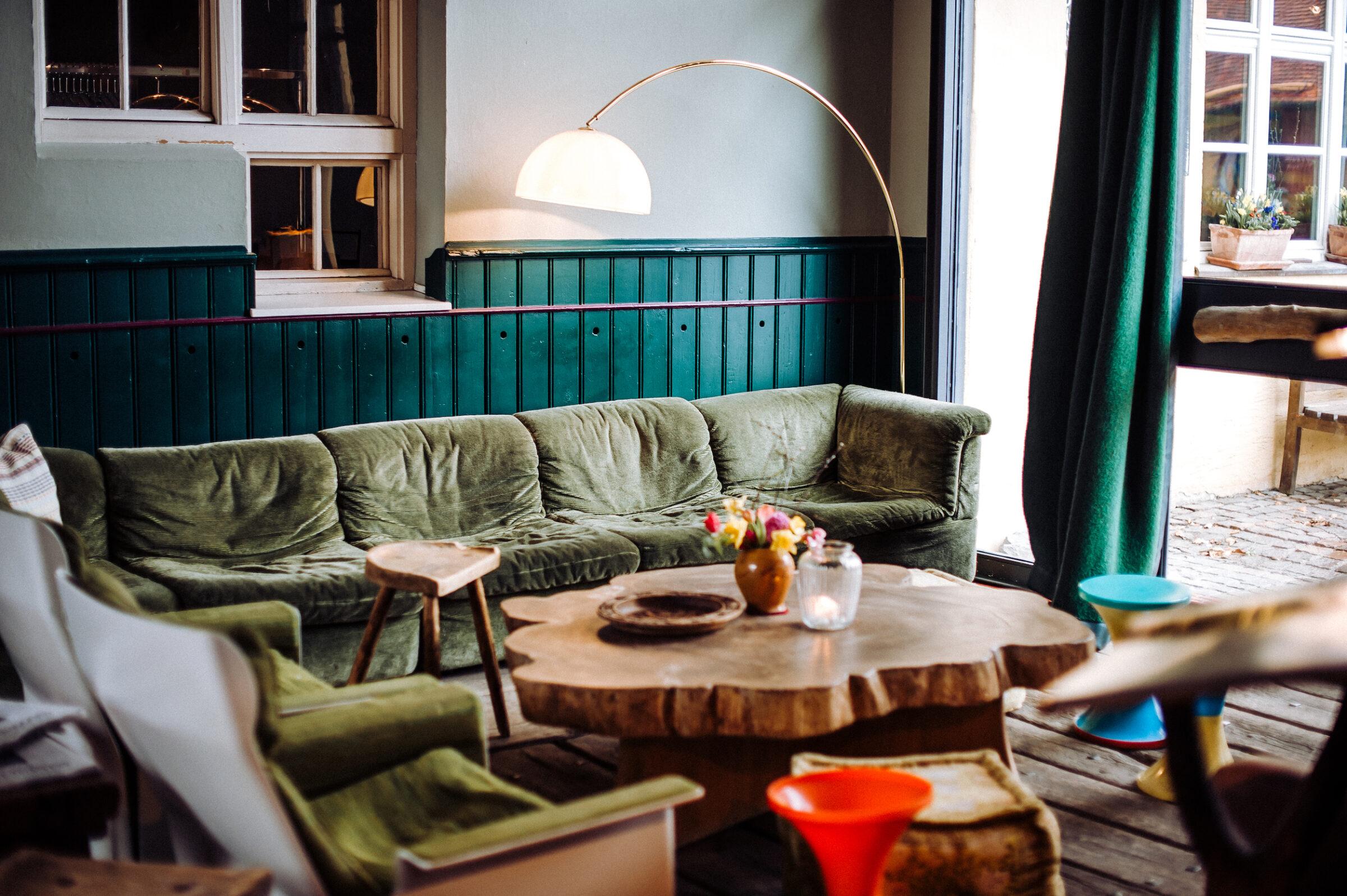 Wintergarten mit besonderen Möbeln, u.. einer dunkelgrünen Couch auf Gut Sonnenhausen im nachhaltigen Hotel