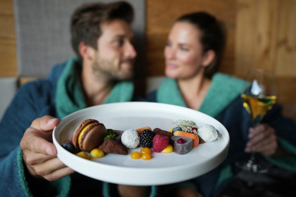 Ein Pärchen hält einen Teller mit Dessertvariationen aus dem nachhaltigen Hotel My Arbor in die Kamera