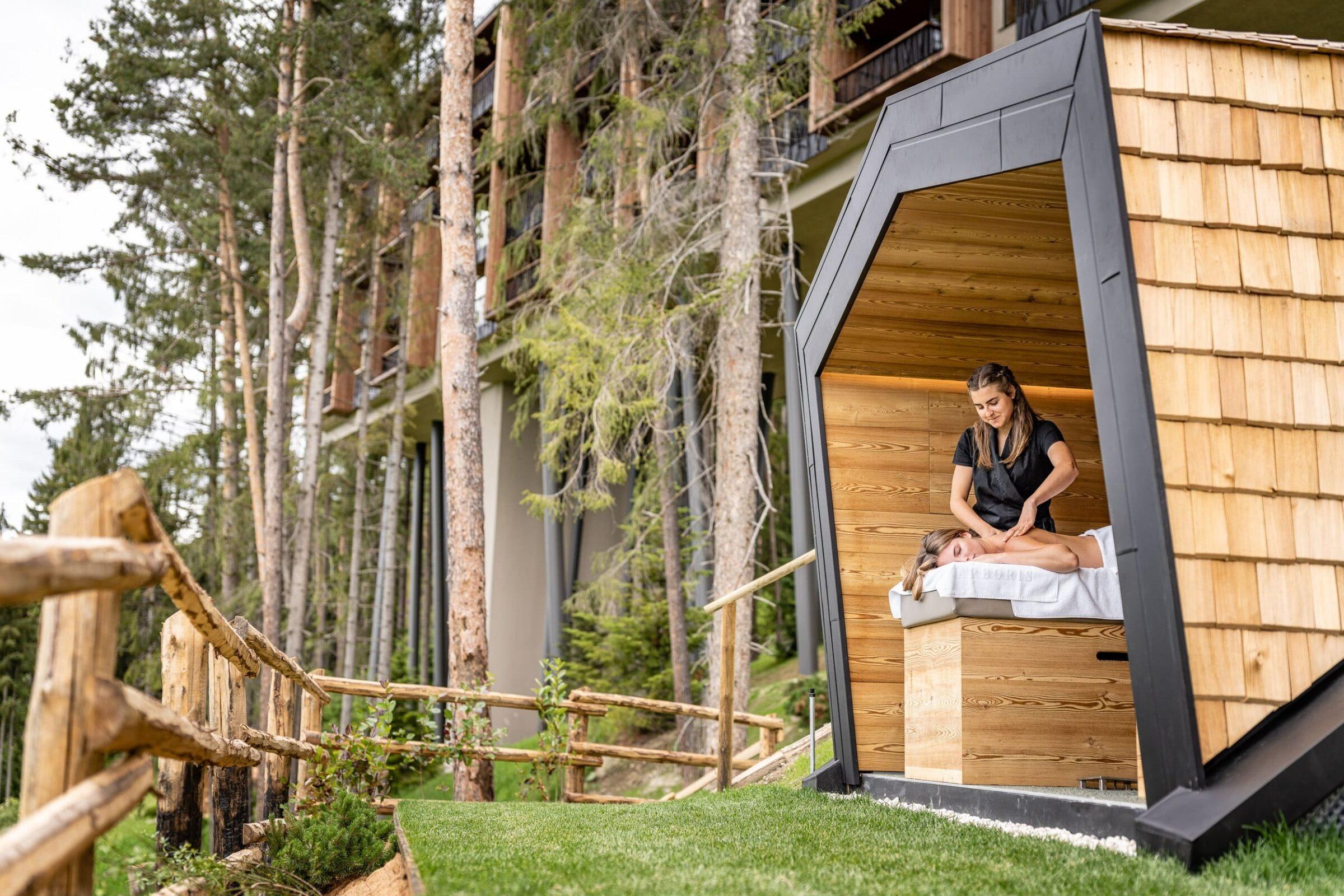 undefinedbekommt eine Massage in einer gemütlichen Holzhütte im Freien des nachhaltigen Hotels My Arbor, umgeben von hohen Bäumen und viel Grün, das Ruhe und Entspannung ausstrahlt.