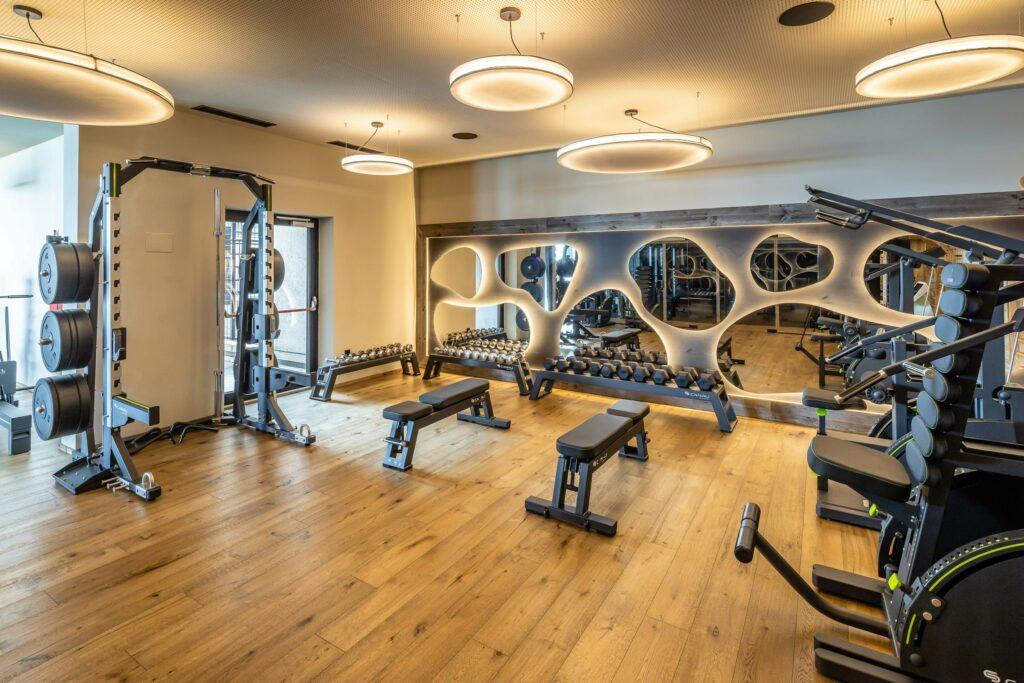 Modernes Gym im nachhaltiben Baumhotel My Arbor bei Brixen mit viel Holz und modernen Geräten sowie organisch geformten Spiegeln an der Wand