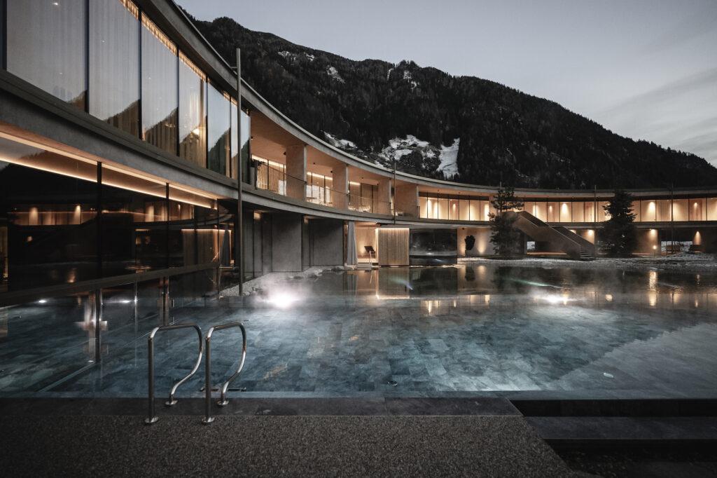 Sustainable and energy self-sufficient aparthotel in South Tyrol: outdoor pool with natural pond in the evening