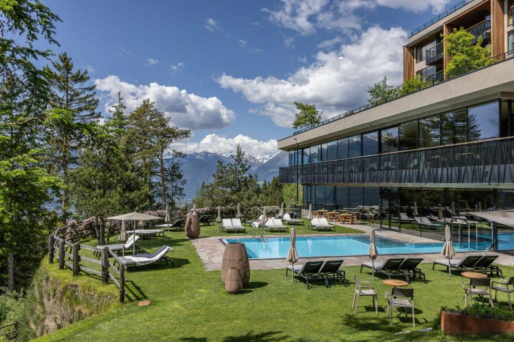 Blick auf den sommerlichen Panorama-Pool des nachhaltigen Wellnesshotels My Arbor bei Brixen; Im Hintergrund: Die Gipfel der Dolomiten