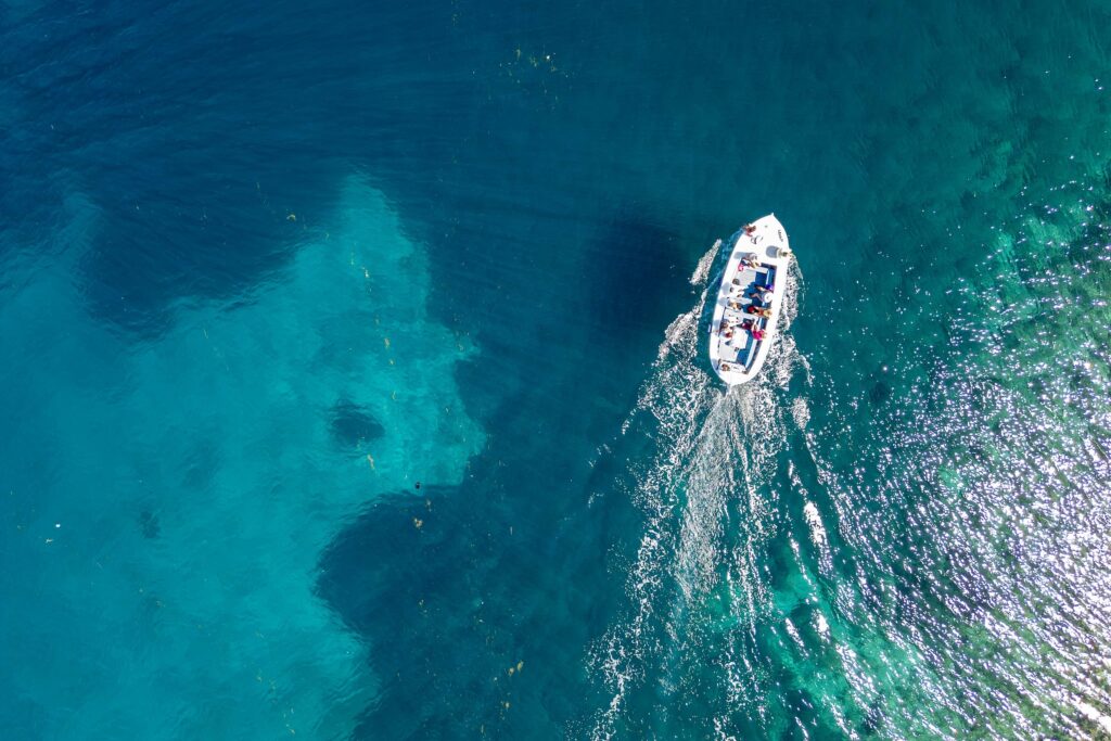 Luftaufnahme eines kleinen Bootes mit mehreren Personen auf klarem blauem Wasser vor der Küste Kroatiens