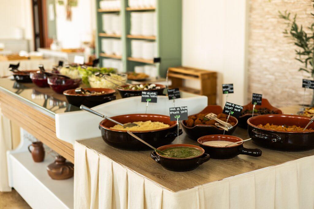 Buffet mit verschiedenen vegetarischen Gerichten in braunen Schalen auf einem mit Stoff bedeckten Tisch im Hotel Korinjak in Kroatien.