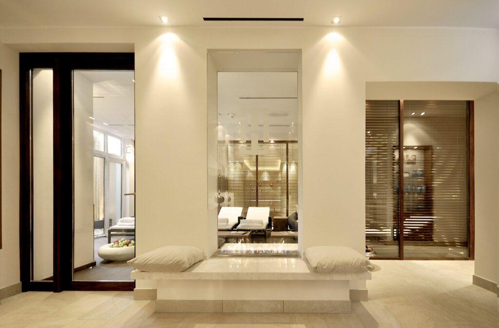 Modern spa in the sustainable boutique hotel SANDglow on the North Sea coast with soft lighting, neutral colors, and wood accents. A central marble bench with cushions provides relaxation and elegance.