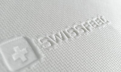 White textured fabric on a mattress with the word “SWISSFEEL” and an embossed cross symbol, conveying a feeling of softness and premium quality.