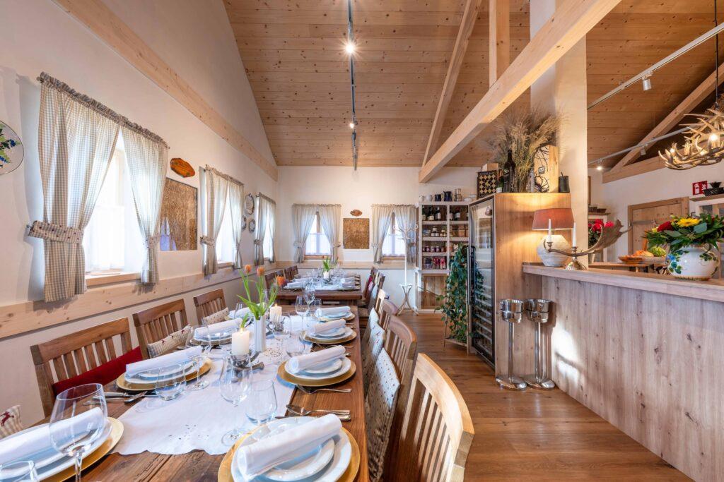Cozy dining room in Ebner 1822's village tavern in Carinthia with wood decor and a table set for several guests. Soft lighting and rustic elements create a warm, inviting atmosphere.