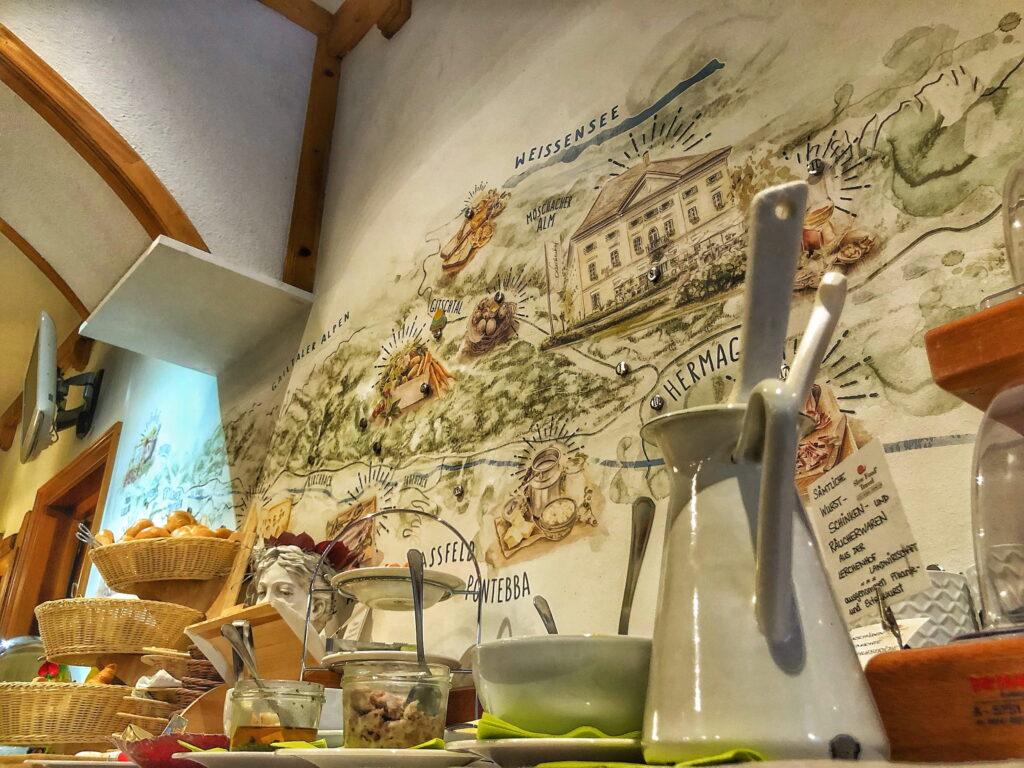 Cozy restaurant interior with a wall map on the wall. Baskets with bread, glasses, and utensils create a warm, inviting atmosphere. Earth tones dominate. Taken at the sustainable Hotel Schloss Lerchenhof.