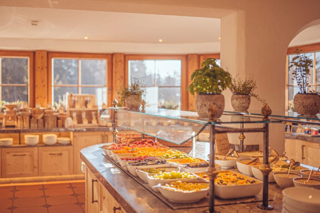 Buffet mit Schalen voller frischem Obst und Müsli in einem hellen Raum mit Holzmöbeln und großen Fenstern im Bioresort Stanglwirt am Wilden Kaiser