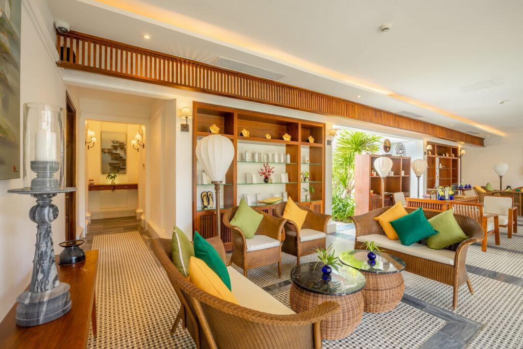 Eine luftige Lounge mit Korb-Sesseln, gläsernen Couchtischen und grünen und gelben Kissen im „The Anam Spa“ des luxuriösen Resorts „The Anam Cam Ranh“ in Vietnam