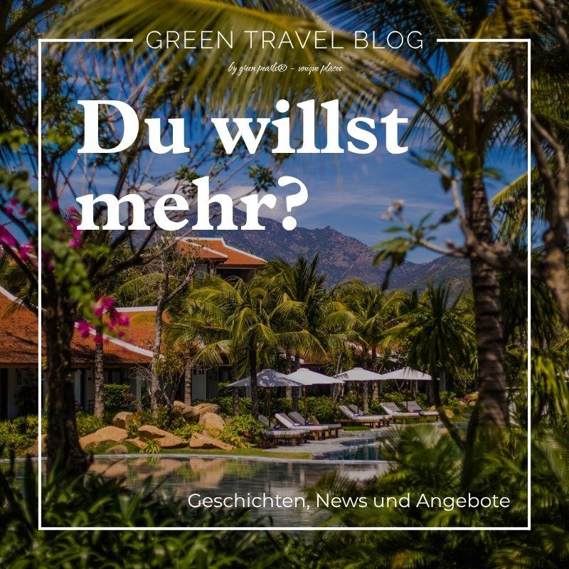 Poolbereich des Resorts mit Liegestühlen und Sonnenschirmen, umgeben von Palmen und tropischen Pflanzen, mit Bergen im Hintergrund