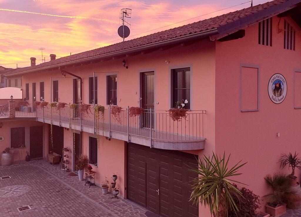 Zweigeschossiges Mehrfamilienhaus mit Balkon und Blumenkästen bei Sonnenuntergang bei „Rocche di Montexelo Vacation Rentals“ im Piemont, Italien