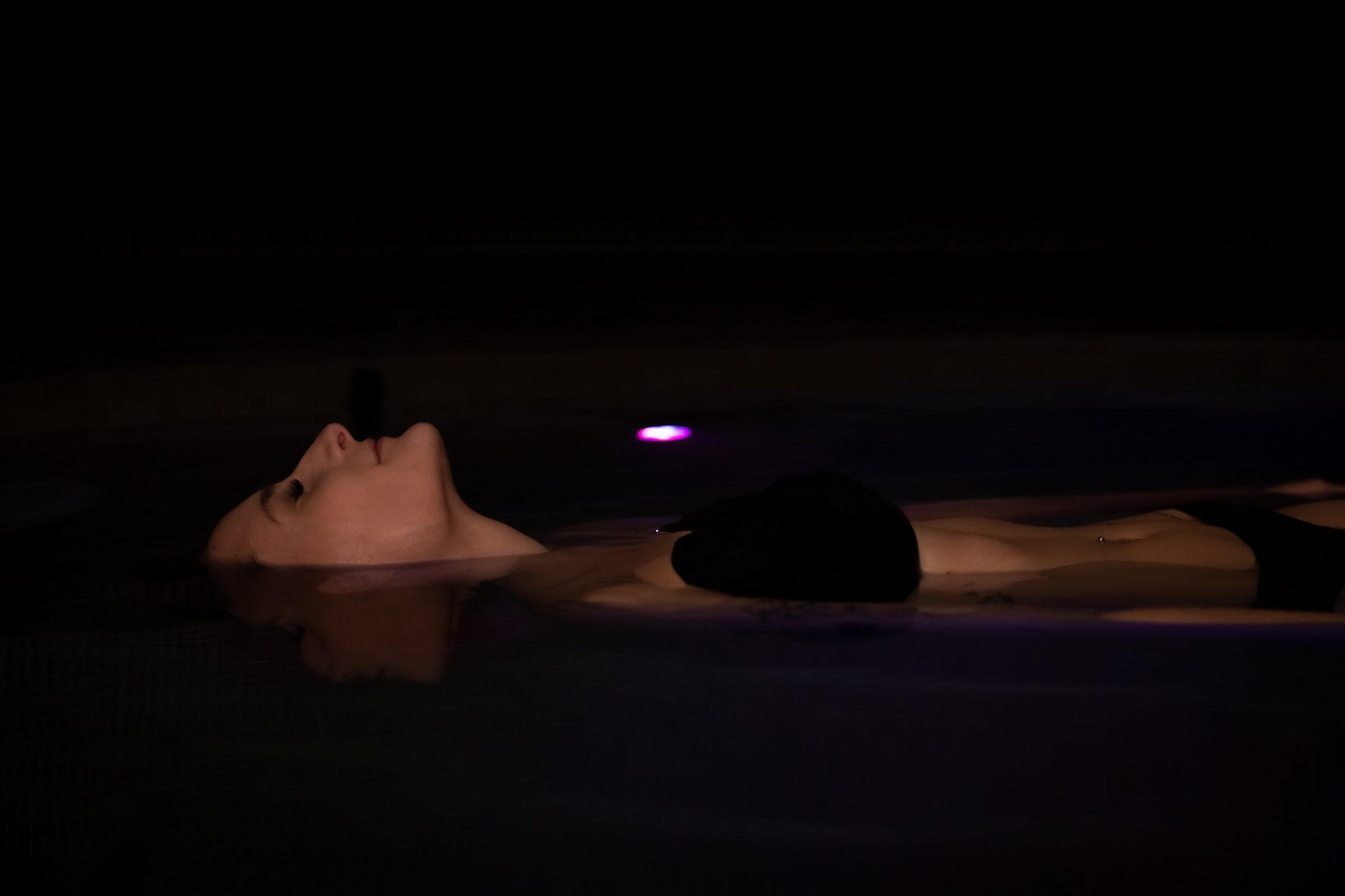 Person liegt entspannt auf dem Rücken im dunklen Wasser des Alpen SoleDom Floating im Klosterhof Spa
